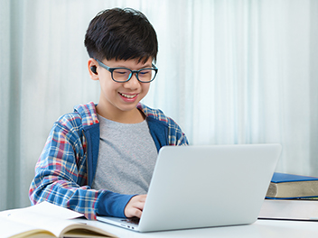 school-aged boy doing homework on laptop