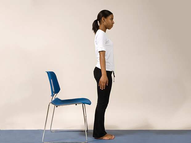 Model demonstrates step 1 of the chair squat exercise